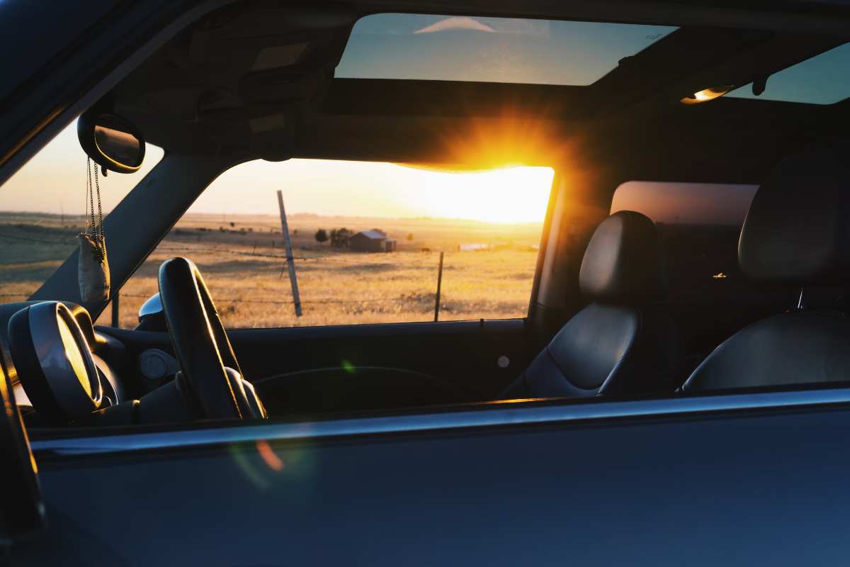 Interno di un'automobile al tramonto con un profumatore appeso allo specchietto retrovisore